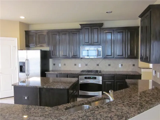 a kitchen with kitchen island granite countertop a sink a stove and a refrigerator