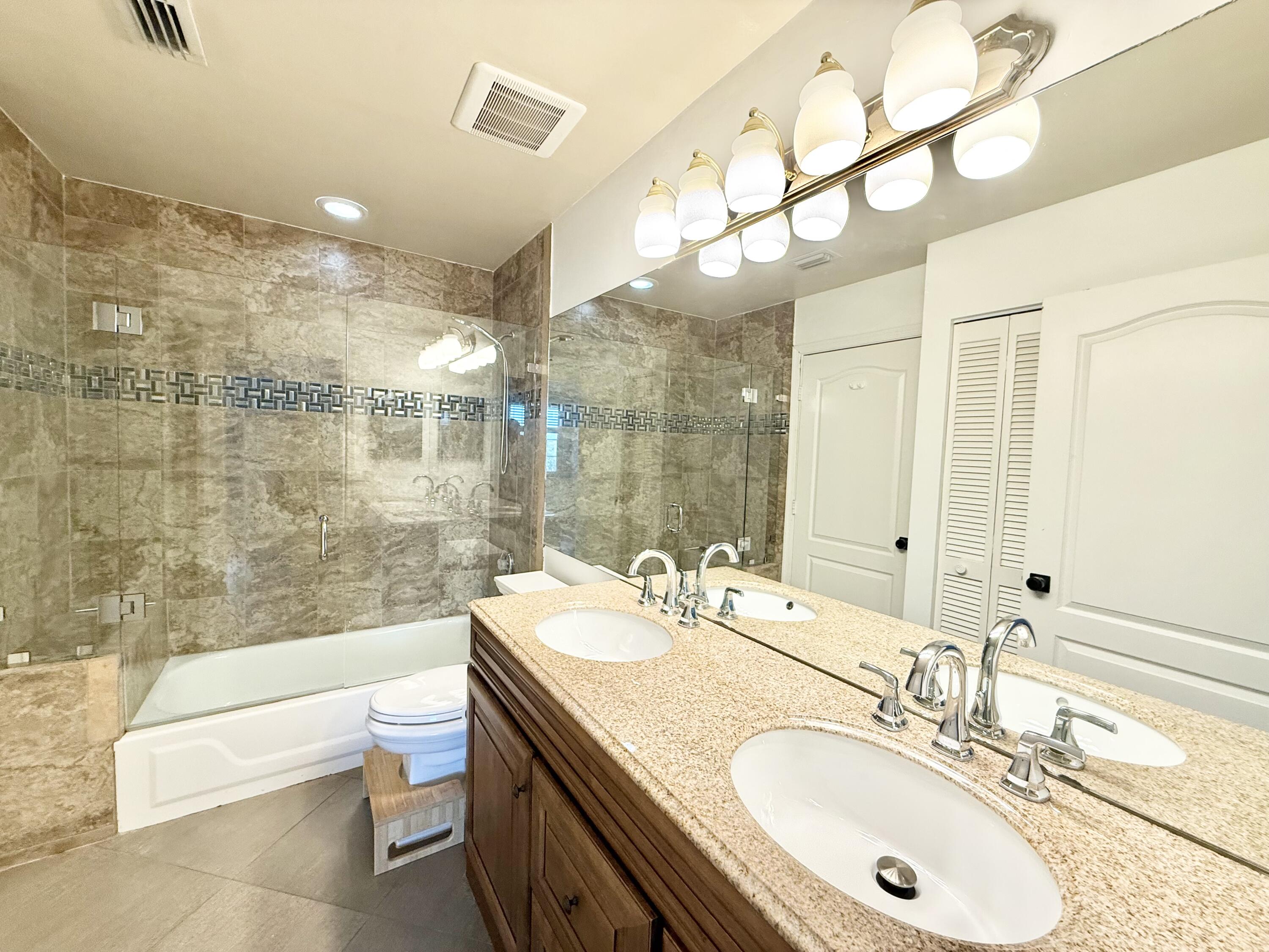 9190 Boca Gardens Parkway, Unit B Boca Raton, FL 33496 - Photo 21 of 35 a bathroom with a granite countertop sink a toilet a mirror a bathtub and shower