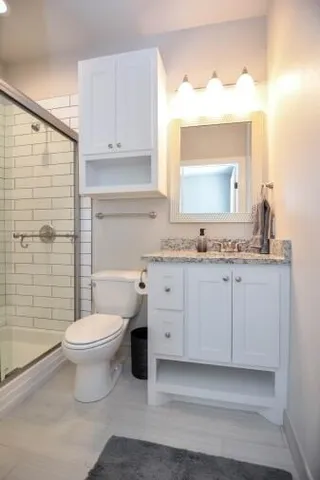 a bathroom with a granite countertop toilet sink and mirror
