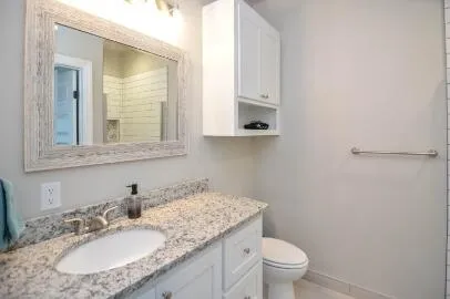 a bathroom with a granite countertop sink a toilet and a mirror