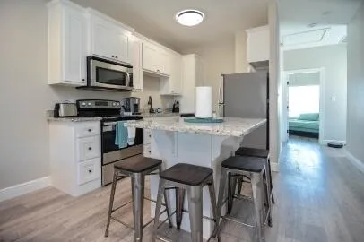 a kitchen with stainless steel appliances granite countertop a stove a sink a microwave a refrigerator with a dining table and chairs