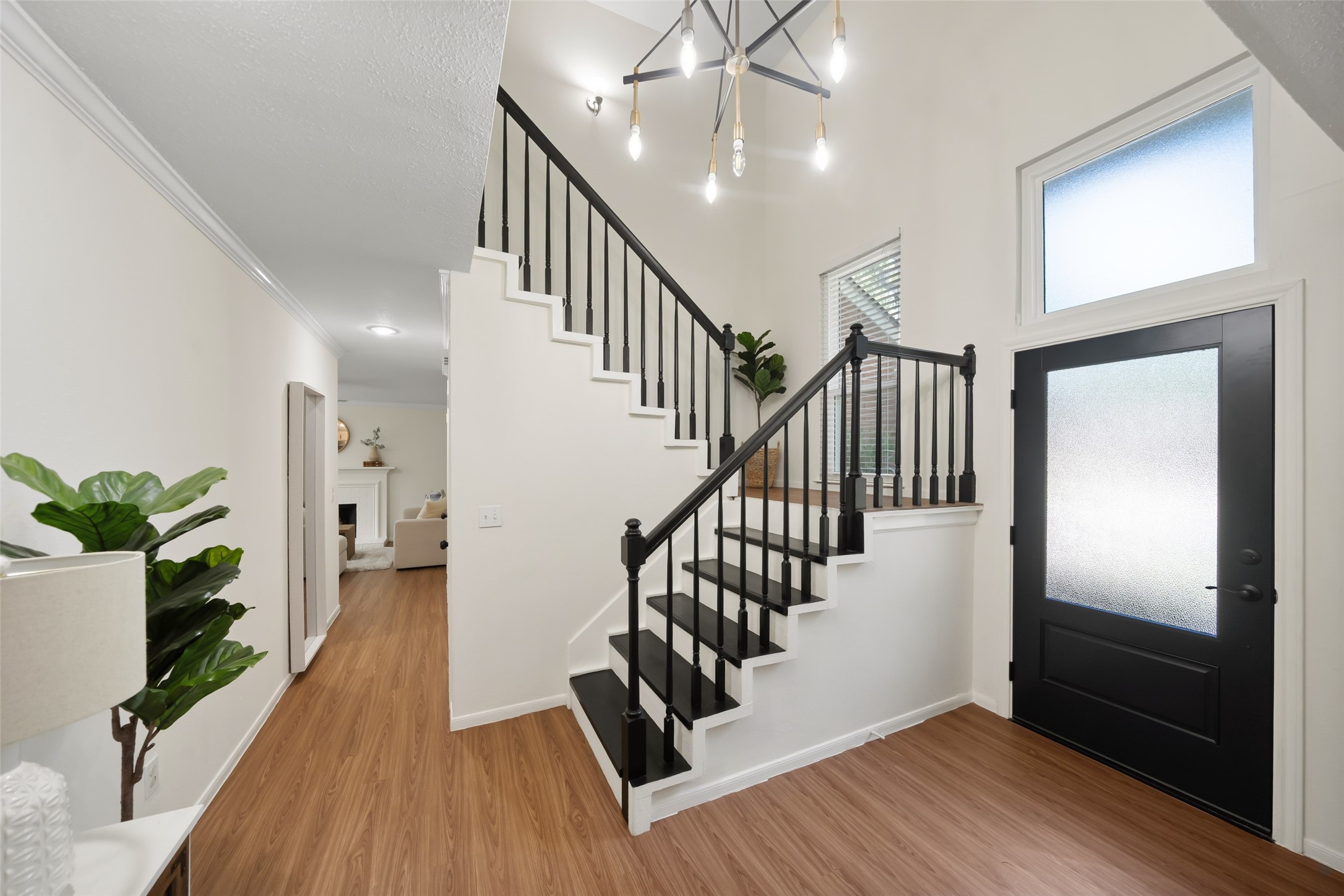 3 East Stony Bridge Circle Spring, TX 77381 - Photo 5 of 42 Bright and welcoming entryway with a modern staircase featuring black railings and steps. The space is complemented by a stylish light fixture and a large frosted glass door, creating an inviting ambiance.