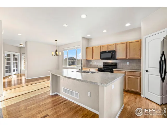 a kitchen with stainless steel appliances granite countertop a sink a stove a refrigerator and a microwave