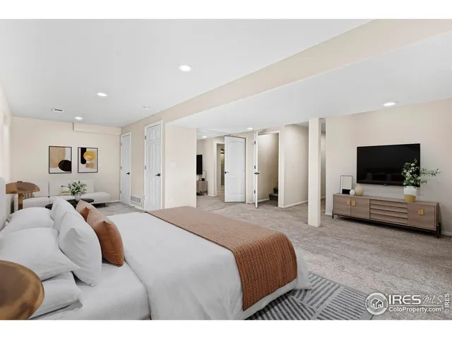 a spacious bedroom with a bed and a flat screen tv