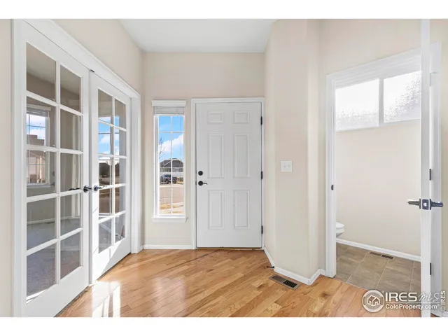 a view of an empty room with wooden floor and windows