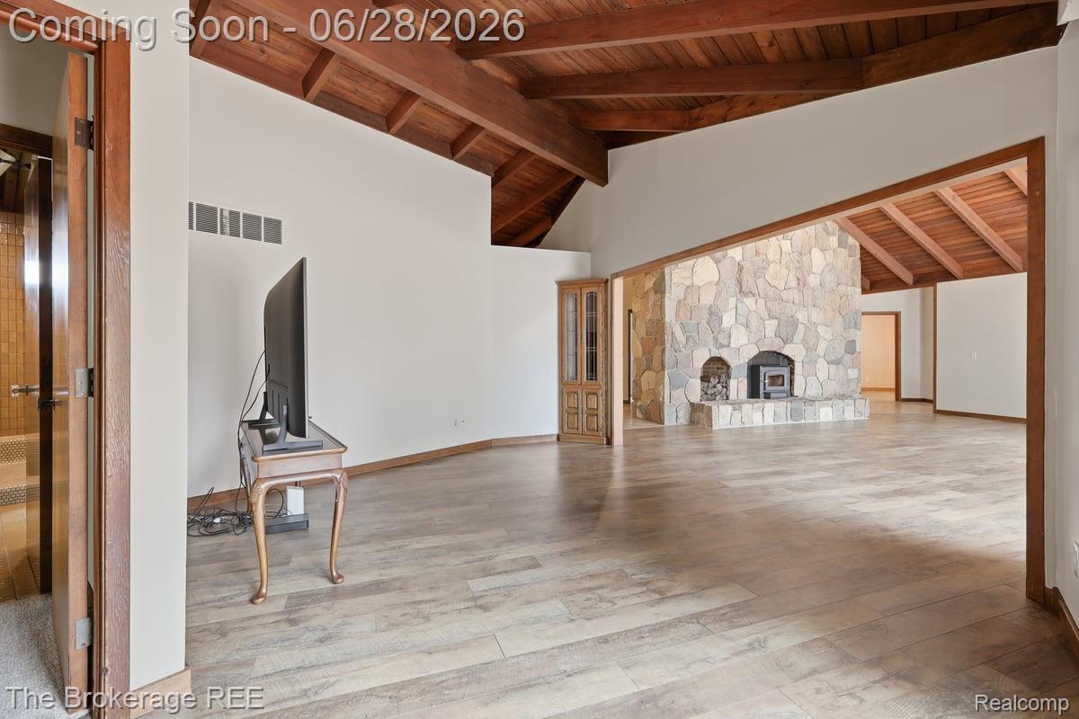 8475 Knox Road Clarkston, MI 48348 - Photo 25 of 71 Spacious interior featuring wood-finish flooring, exposed beam ceiling, a stone fireplace, and an arched entry