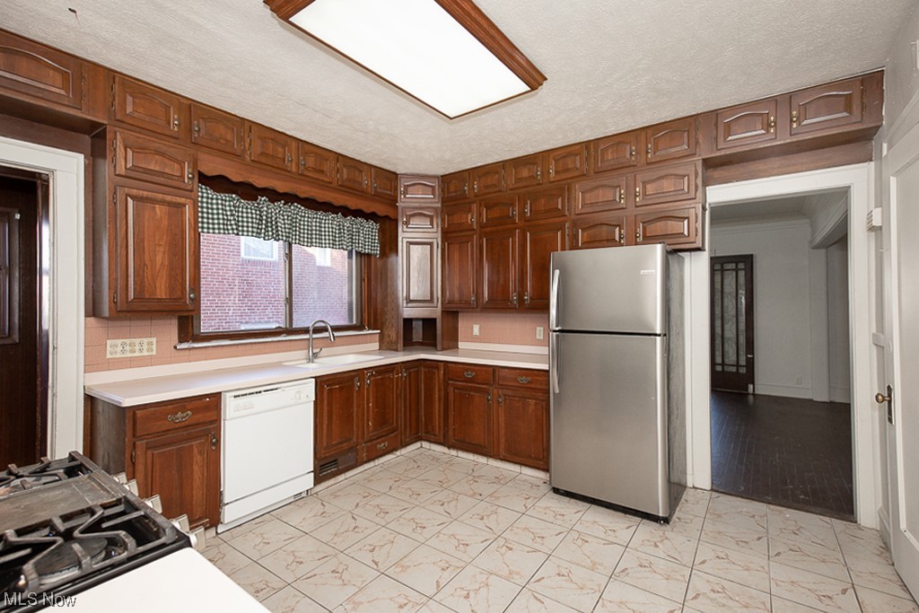 4574 Broadview Road Cleveland, OH 44109 - Photo 6 of 30 Kitchen featuring white dishwasher, stainless steel fridge, sink, and light tile floors