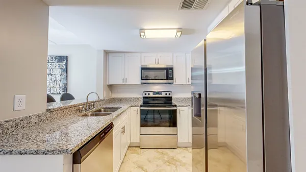 a kitchen with a granite countertop sink stove and refrigerator