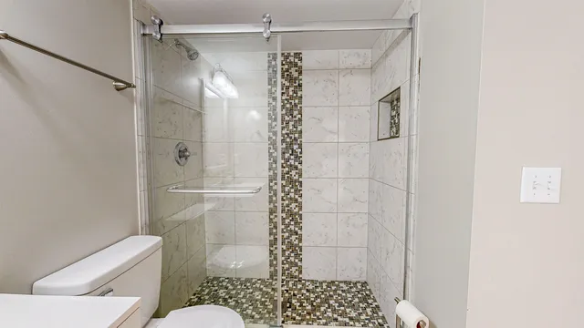 a bathroom with a shower a toilet and a window