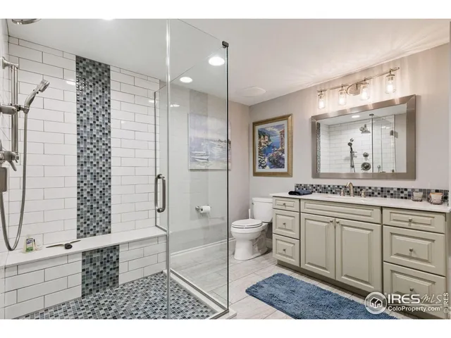 a bathroom with a granite countertop sink a toilet a mirror and shower