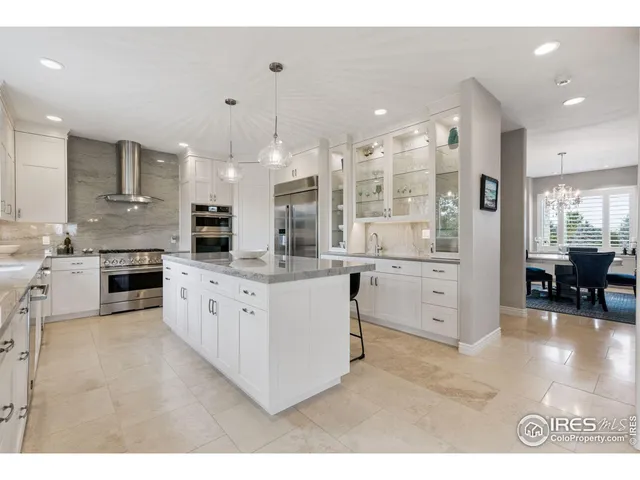 a large white kitchen with stainless steel appliances kitchen island granite countertop a large counter top and stove