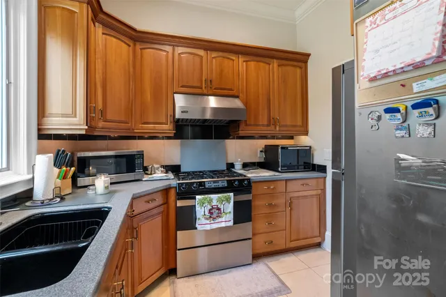 a kitchen with stainless steel appliances granite countertop a stove a sink and a microwave