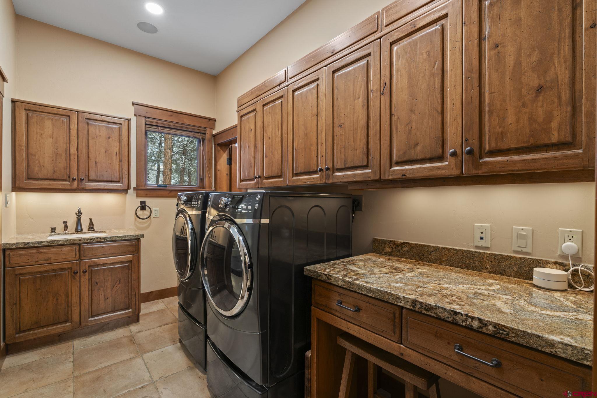 680 The Golden Dipper Road Durango, CO 81301 - Photo 20 of 35 a utility room with granite countertop a sink a washer and dryer