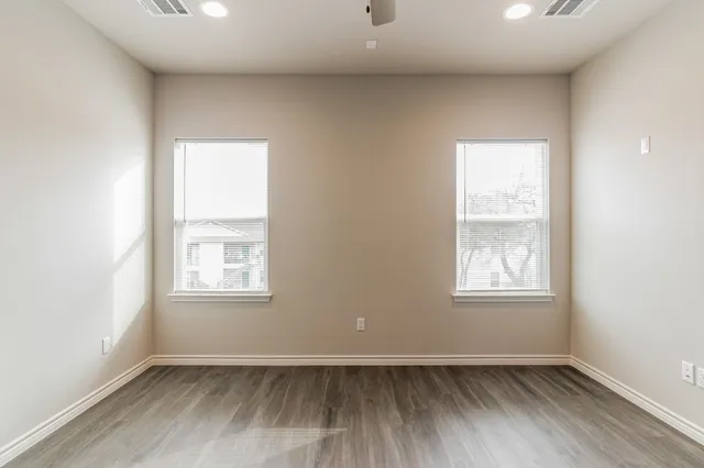 an empty room with wooden floor and windows