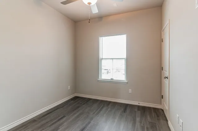 a view of empty room with window and wooden floor