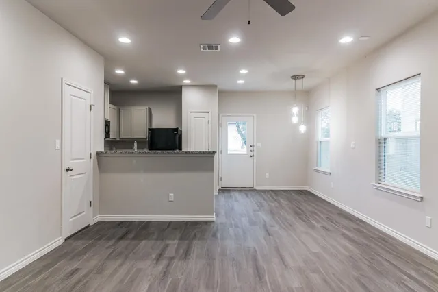 an empty room with wooden floor and windows