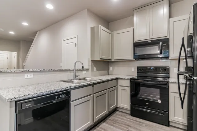 a kitchen with stainless steel appliances granite countertop a sink stove microwave and refrigerator