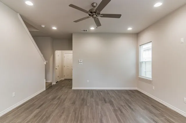 an empty room with wooden floor cabinet and windows