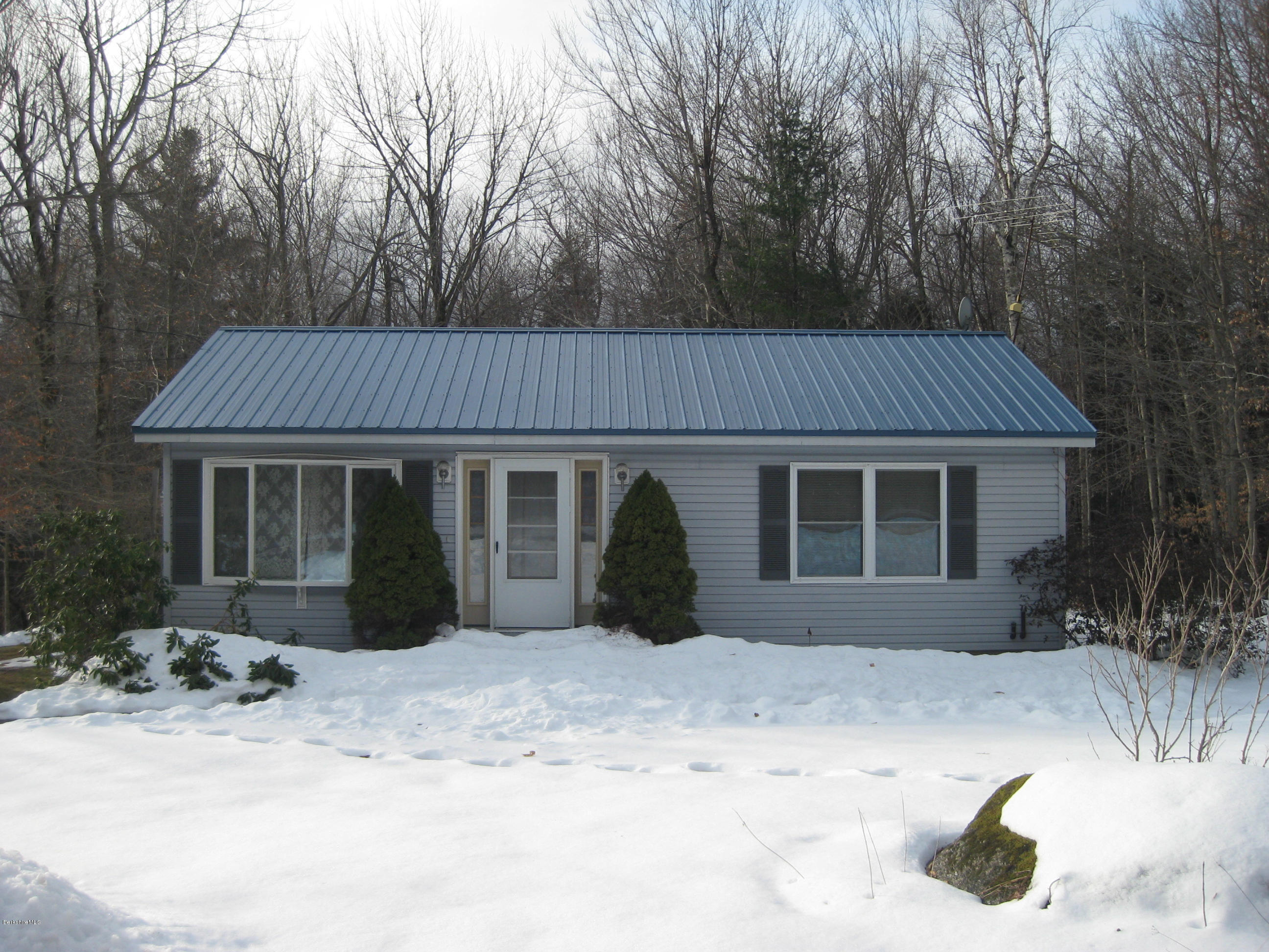 576 Loop Road Savoy, MA 01256 - Photo 8 of 23 a front view of a house with a yard covered in snow and trees in the background