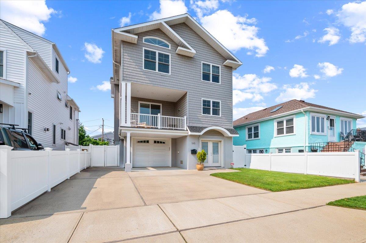 View of front of house with a balcony, driveway, a garage, and french doors