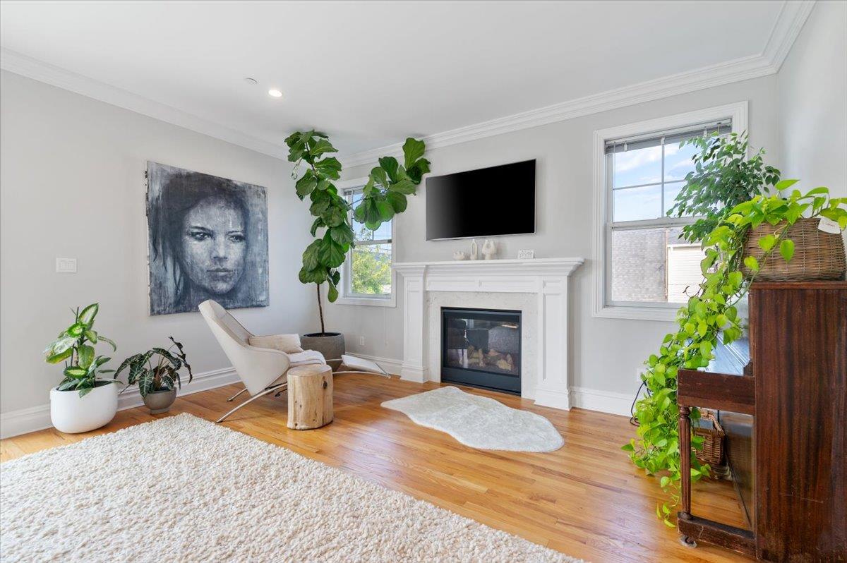 545 East Fulton Street Long Beach, NY 11561 - Photo 17 of 41 Living area with crown molding, plenty of natural light, a glass covered fireplace, and wood finished floors