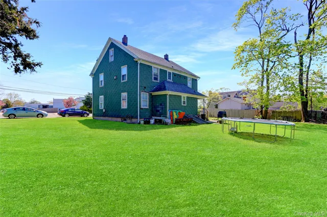 a view of an apartment with a big yard and large trees