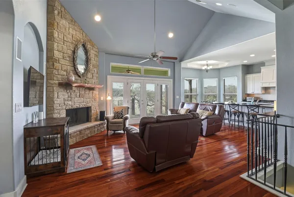 a living room with furniture large windows and wooden floor