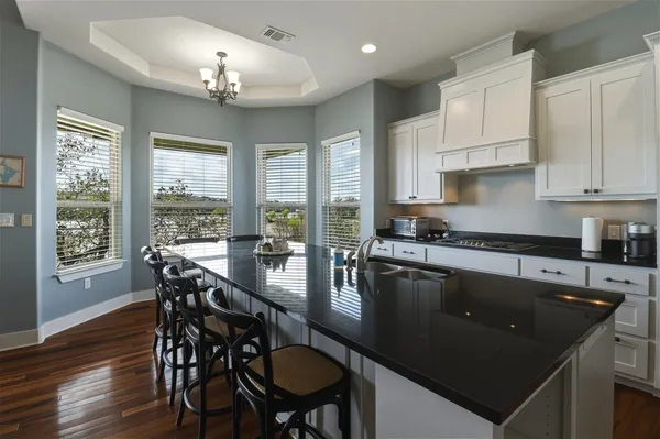 a kitchen with granite countertop a stove a sink a dining table and chairs