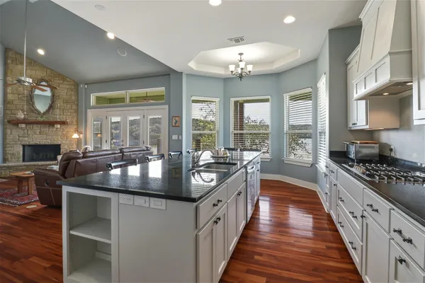 a kitchen with stainless steel appliances granite countertop a stove and a view of living room