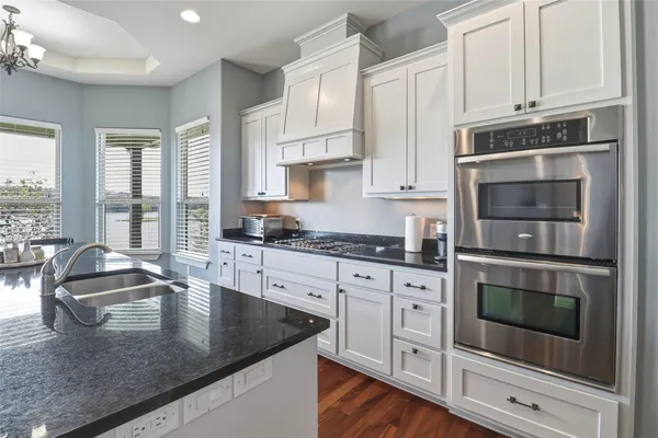 a kitchen with granite countertop white cabinets and stainless steel appliances