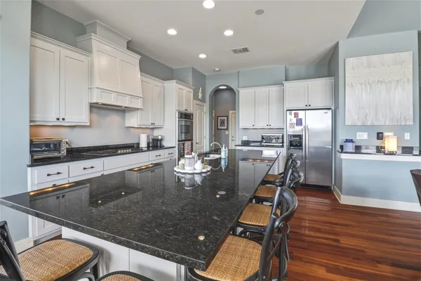 a kitchen with stainless steel appliances granite countertop a table chairs sink refrigerator and cabinets