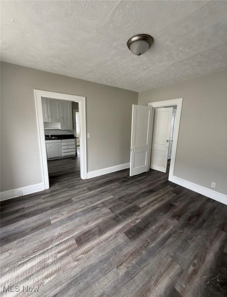 1743 Algonac Road Cleveland, OH 44112 - Photo 5 of 19 Unfurnished bedroom featuring a textured ceiling and dark wood-type flooring
