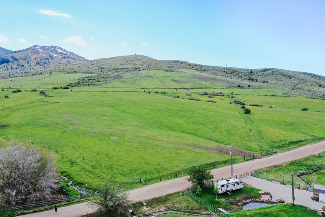 6700 North Capitol Hill Road Preston, ID 83263 - Photo 5 of 28 Expansive green acreage with distant mountains, a gravel road, and a paved driveway