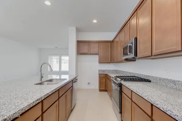 a kitchen with granite countertop a sink a stove and cabinets