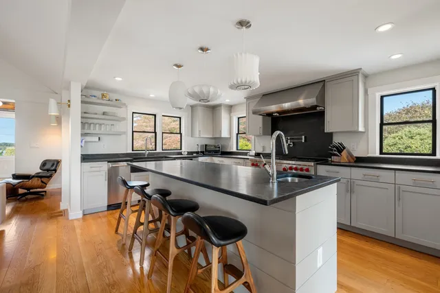 a kitchen with granite countertop a sink a counter top space stainless steel appliances and a chandelier