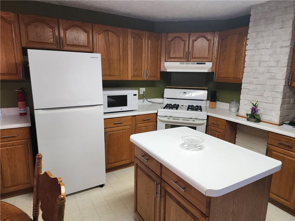 844 Rose Stop Road New Castle, PA 16101 - Photo 4 of 28 a kitchen with a refrigerator a stove a sink and white cabinets