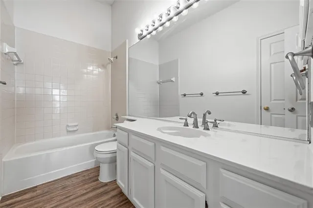 a bathroom with a granite countertop sink toilet a large mirror a bathtub and shower