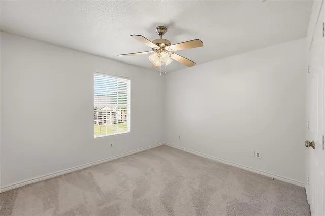 an empty room with a window and a fan