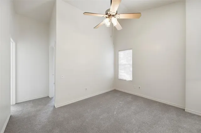 an empty room with a fan & a window