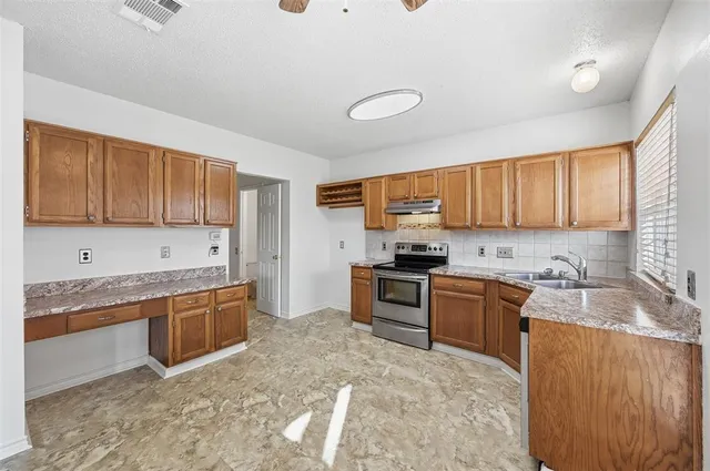 a kitchen with stainless steel appliances granite countertop a stove top oven a sink dishwasher a dining table and chairs with wooden floor