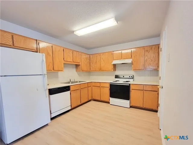 a kitchen with granite countertop a refrigerator stove top oven and sink