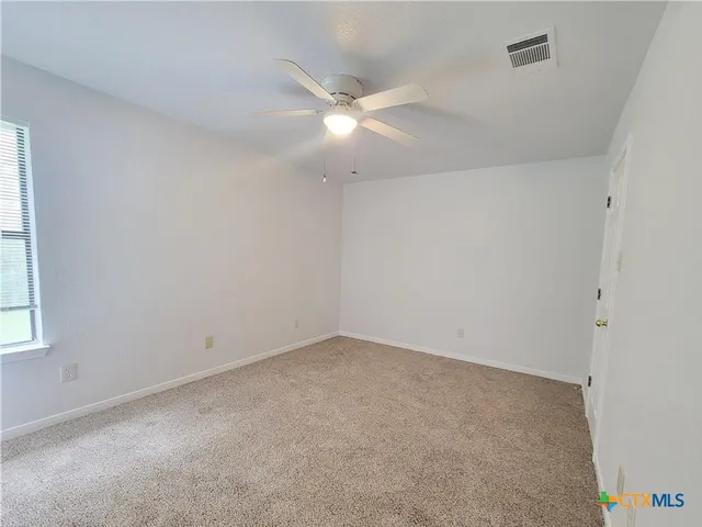 an empty room with a window and ceiling fan