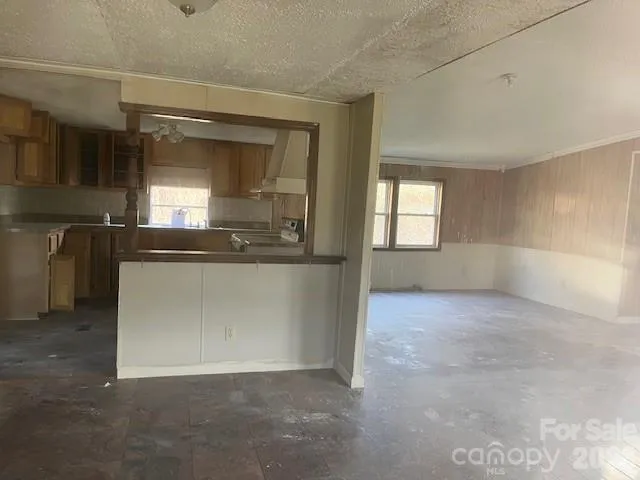 an empty room with a kitchen view and windows