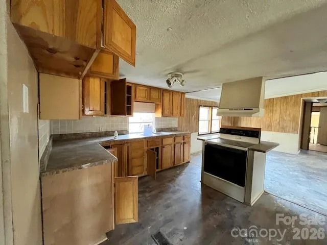 a kitchen with stainless steel appliances granite countertop a sink a stove top oven a counter space and cabinets