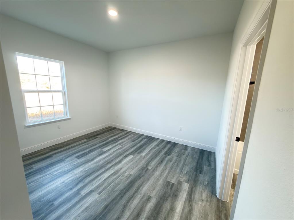2703 Southwest 162nd Street Road Ocala, FL 34473 - Photo 22 of 39 an empty room with wooden floor and windows