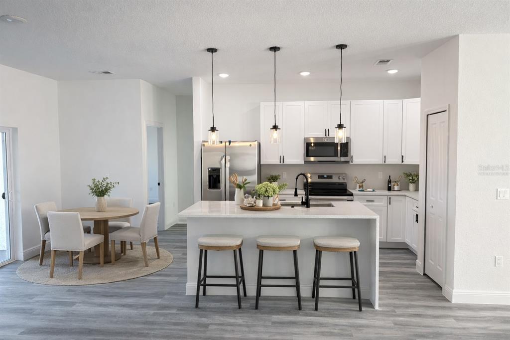 2703 Southwest 162nd Street Road Ocala, FL 34473 - Photo 5 of 39 a kitchen with stainless steel appliances kitchen island granite countertop a dining table chairs and white cabinets