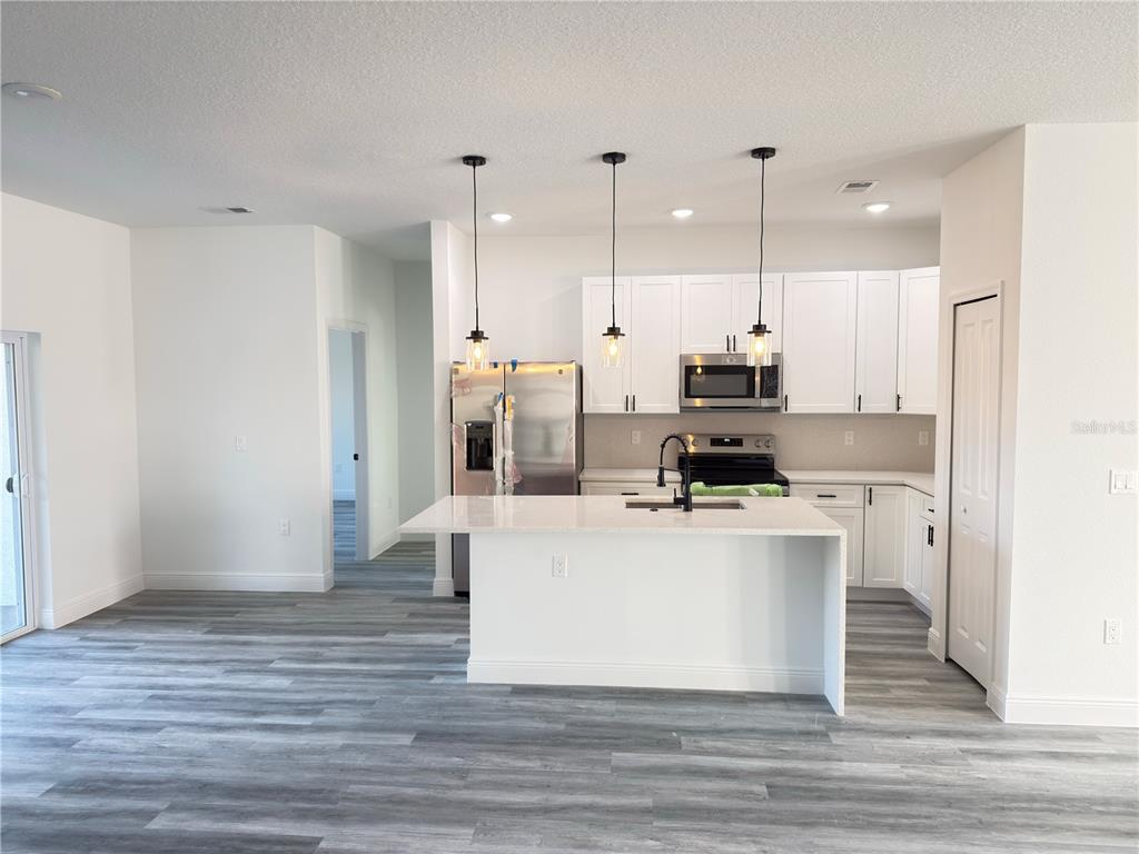 2703 Southwest 162nd Street Road Ocala, FL 34473 - Photo 6 of 39 a kitchen with kitchen island a stove top oven a sink and white cabinets with wooden floor
