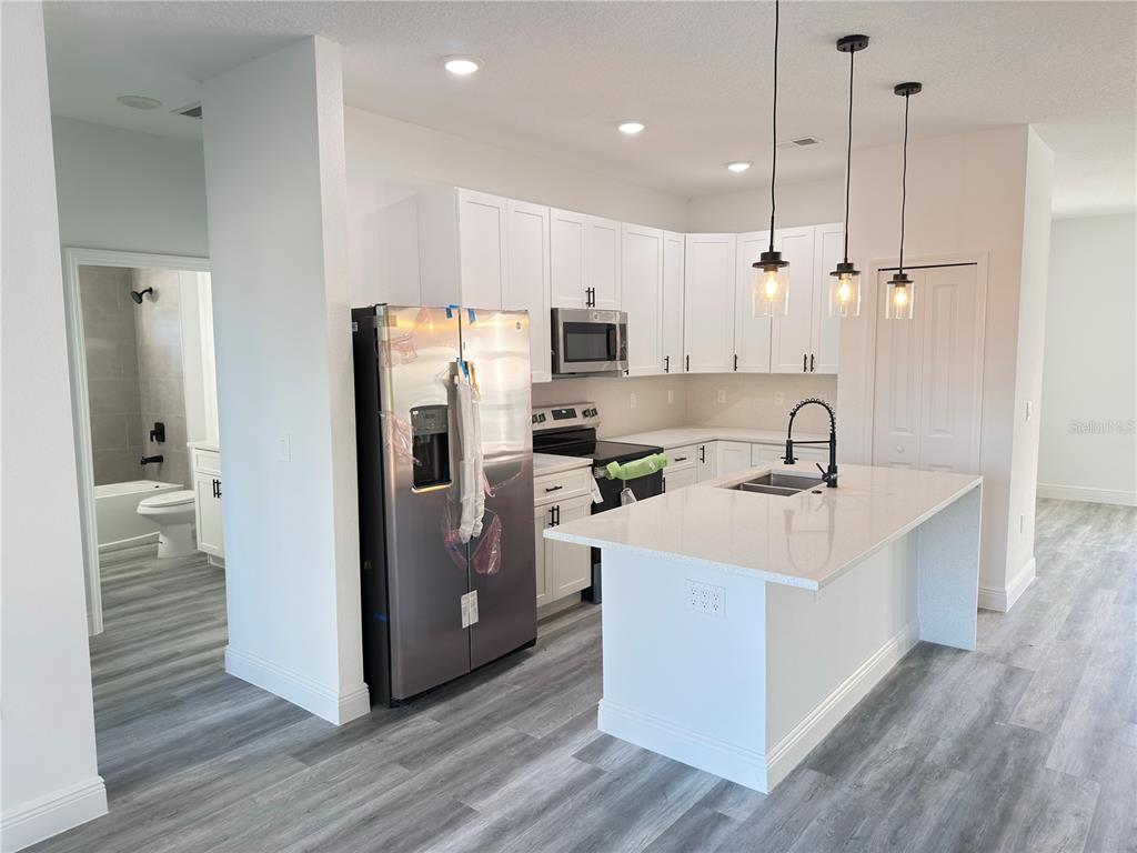 2703 Southwest 162nd Street Road Ocala, FL 34473 - Photo 7 of 39 a kitchen with stainless steel appliances a sink a stove a refrigerator cabinets and wooden floor