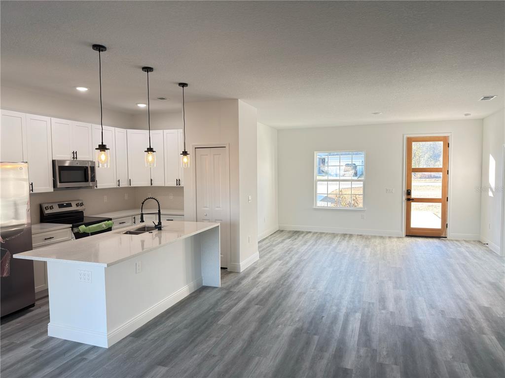 2703 Southwest 162nd Street Road Ocala, FL 34473 - Photo 9 of 39 a large kitchen with stainless steel appliances granite countertop a stove a sink and white cabinets with wooden floor