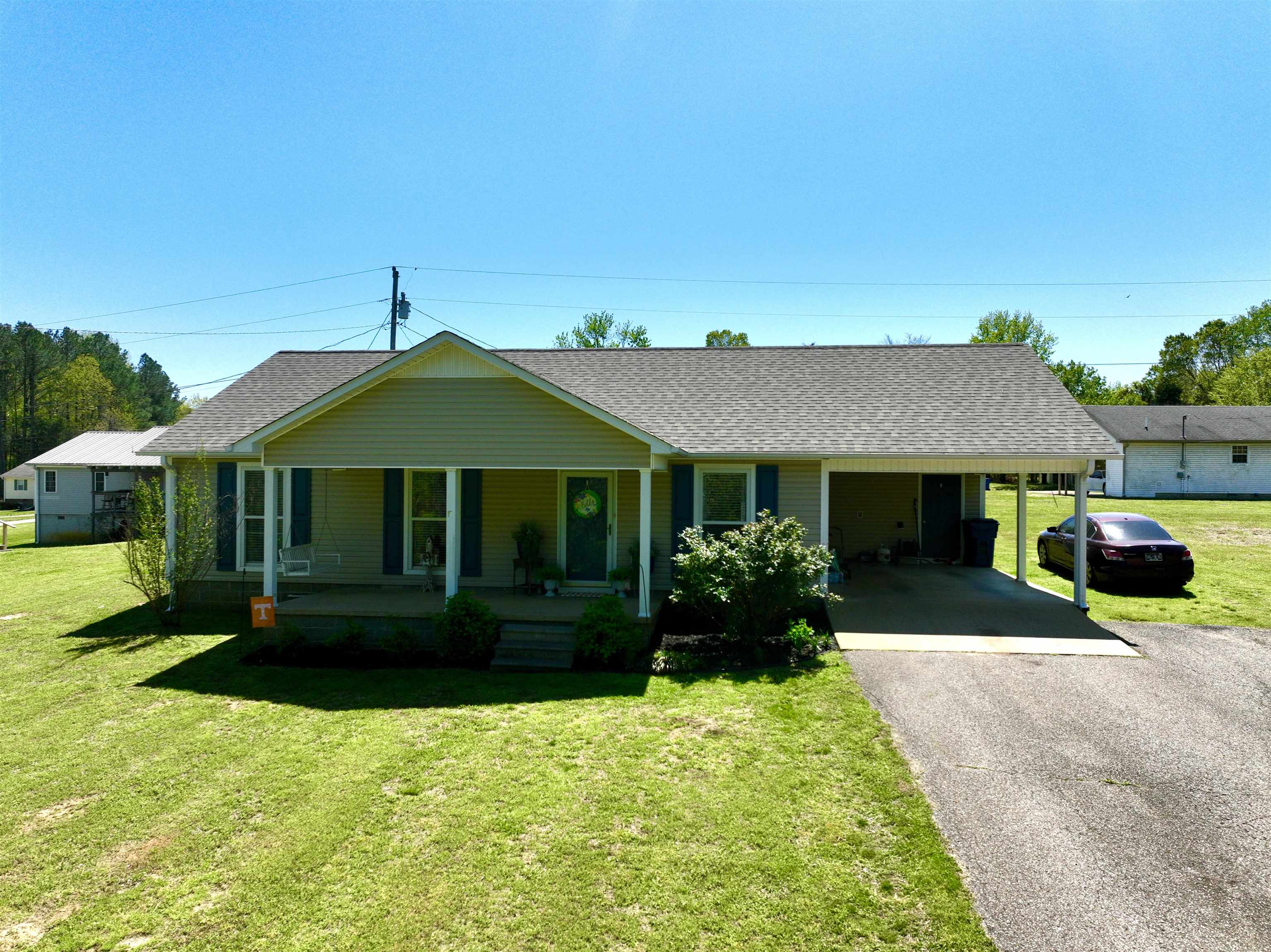 228 Edgewood Drive Adamsville, TN 38310 - Photo 2 of 37 View of front of house featuring an attached carport, covered porch, a front lawn, a shingled roof, and driveway